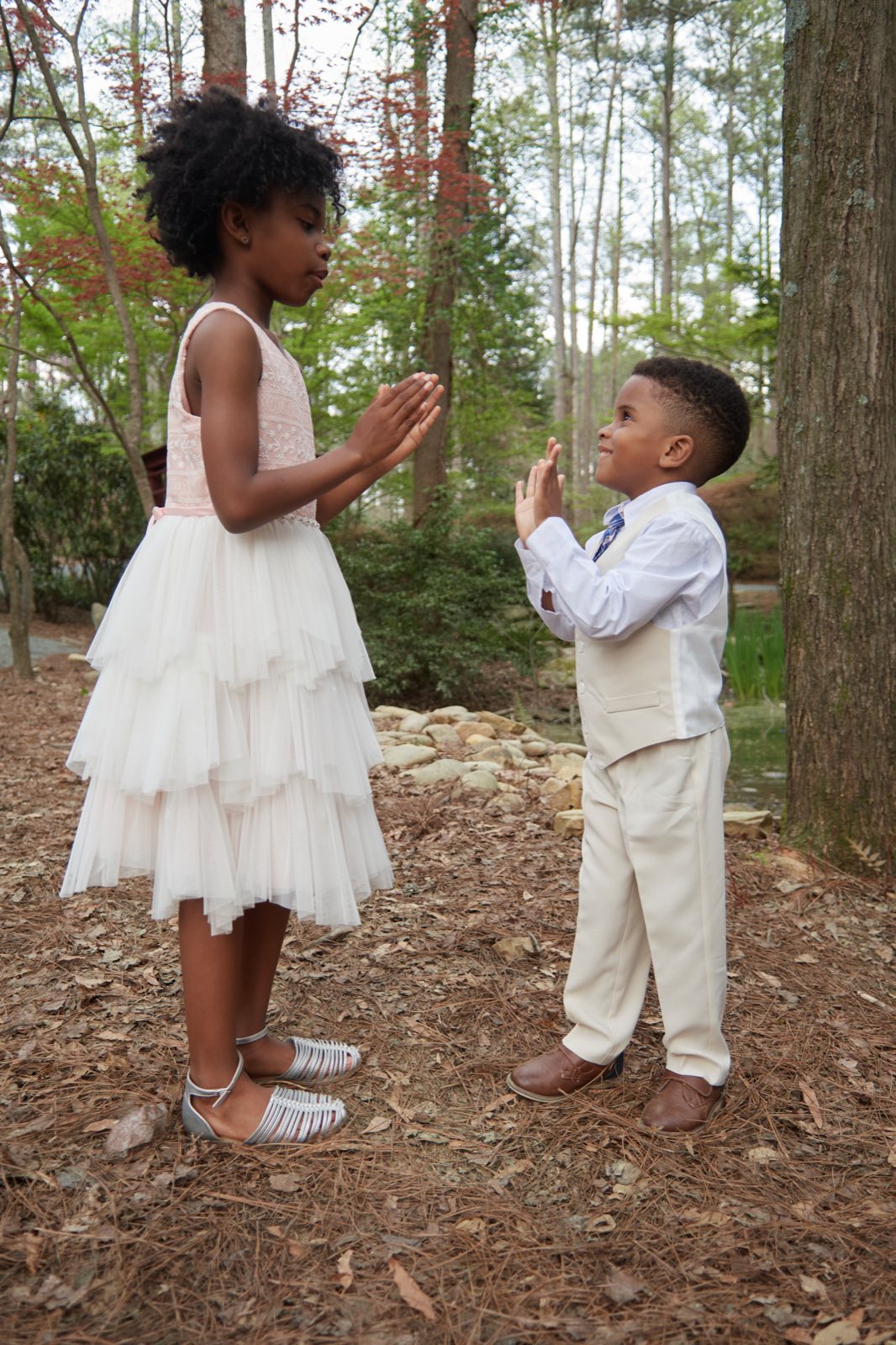 The two children facing each other on a wooded path.