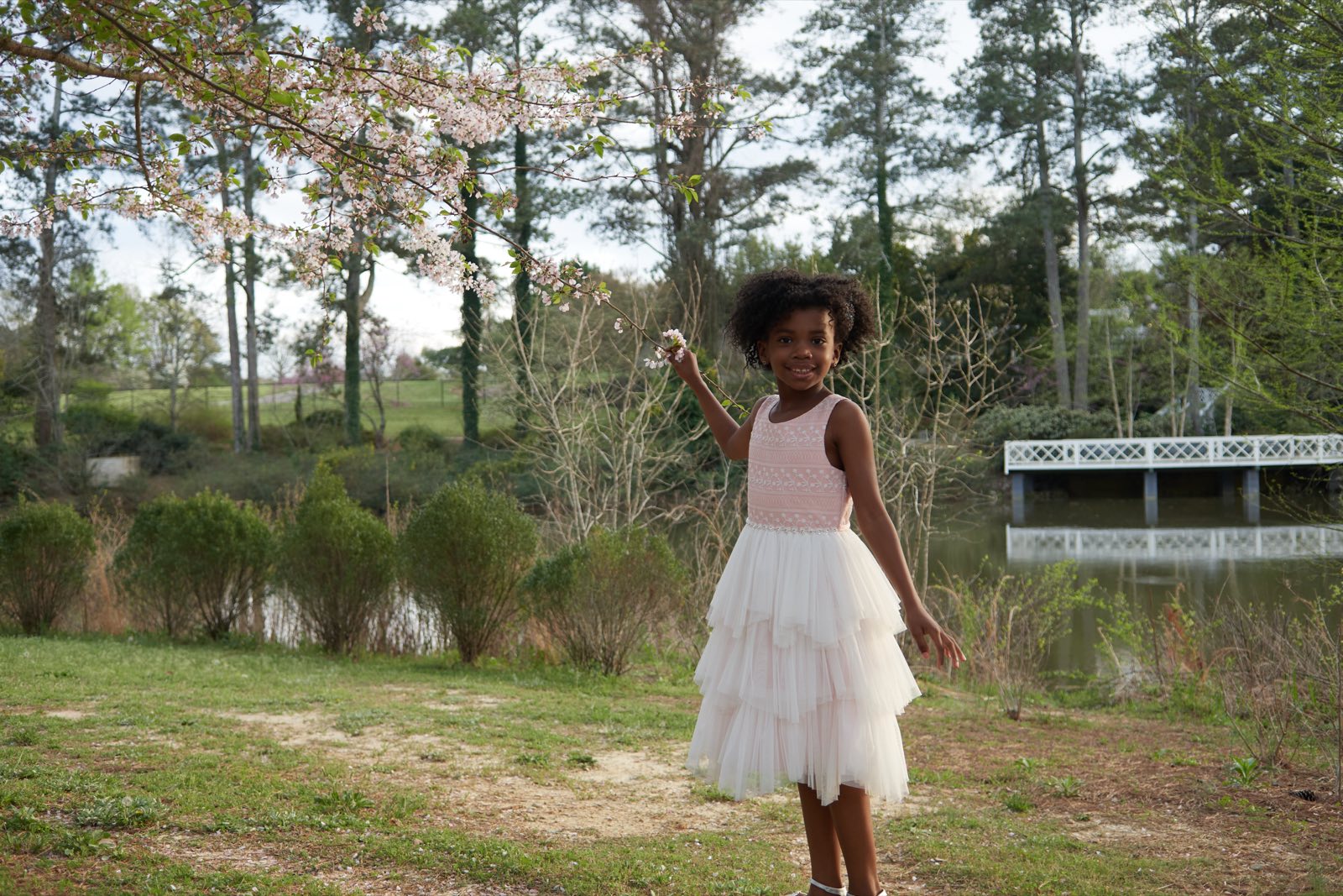 A girl in a white dress walking through an open field.