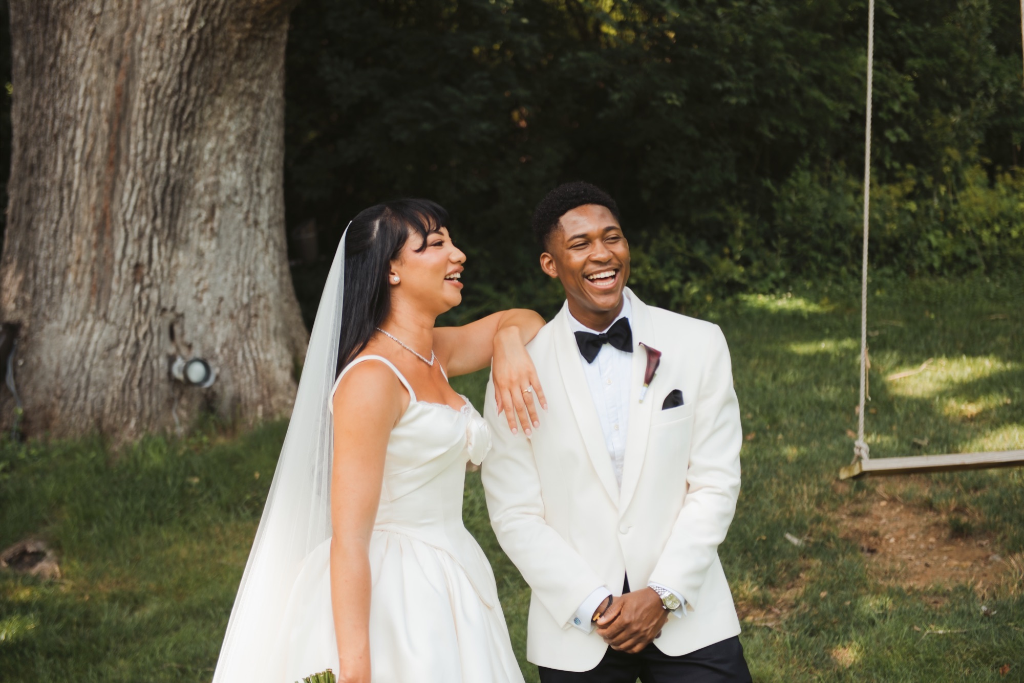 The couple laughing together beside the oak and the rope swing.
