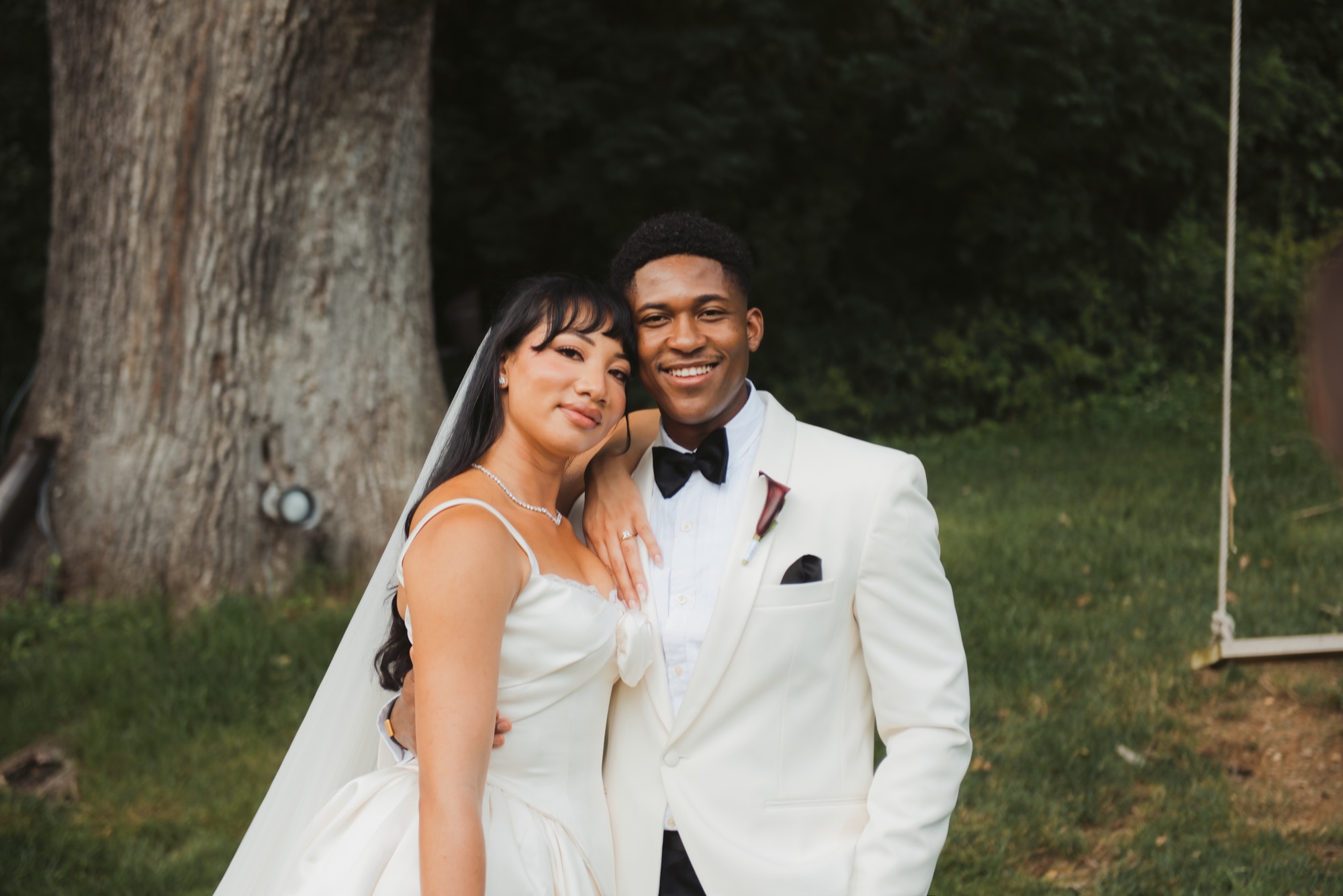 The couple cheek to cheek, both smiling, with the oak behind them.