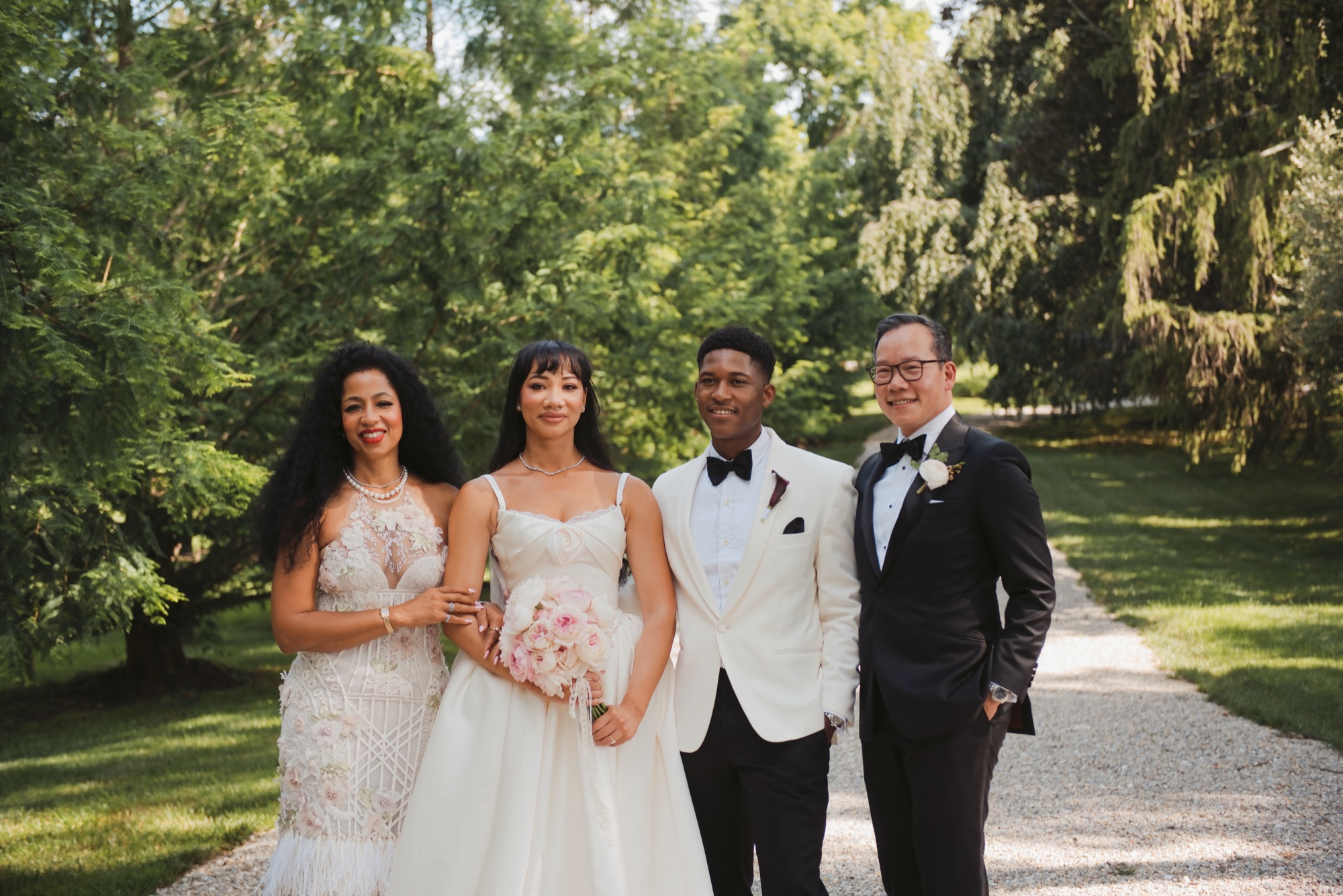 The couple standing with two loved ones on the gravel drive.
